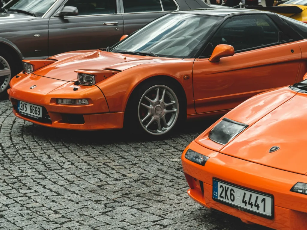 two orange sports cars parked next to each other