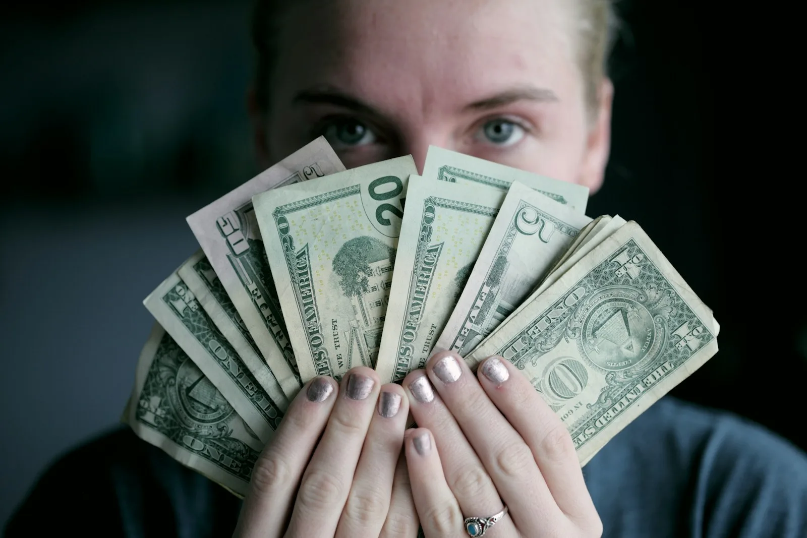 person holding fan of U.S. dollars banknote